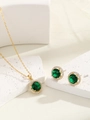 Close-up of golden jewelry set with emerald green stones and zircon accents on marble - Gold Green Zirconia