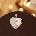 Macro shot of silver heart pendant with pavé cubic zirconia and a red gemstone - Silver Edge Tai Chi