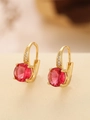 Close-up of gold earrings featuring a round red ruby zircon and small white crystals - Round (TE-09701-01)