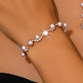 Macro shot of an S-shaped wavy pearl bracelet with rhinestones on a woman's wrist - Gold Pearl Bracelet (747)