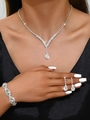 Gros plan d'un ensemble collier et boucles d'oreilles en strass porté sur une robe de soirée - Collier Boucles d'Oreilles Bracelet / Argent