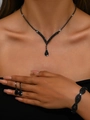 Gros plan d'un ensemble de collier et boucles d'oreilles en strass noirs sur un mannequin - Collier Boucles d'Oreilles Bracelet / Noir