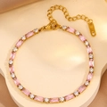 Detail van gouden armband met roze zirkonia en karabijnsluiting op een standaard - Goud Roze Zirkonia