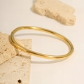Détail du bracelet en acier inoxydable doré avec charnière latérale sur un fond en pierre - Bracelet jonc à charnière lisse / Or