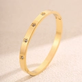 Gros plan du bracelet charnière en acier doré avec quatre breloques fleurs en cristal - Motif Fleur de Prunier / Or