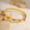 Elegant gold plated stainless steel bangle featuring five small floral motifs with crystals - Gold Flower Bangle