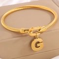 Gouden gedraaide kabelarmband met een ronde hanger en een getextureerde letter G - Gouden Armband Letter G