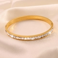 Detailed close-up of a gold-plated bangle with square-cut cubic zirconia in a bezel setting - Gold
