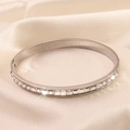 Detail of silver stainless steel bangle with channel-set square zircons on silk background - Silver