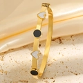 Détail du jonc en titane doré avec cœur sur pierre beige et fond de soie jaune - Or Noir Blanc Émail Cœur Bracelet