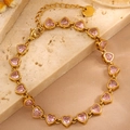 Detail eines Armbands mit rosa Kristallherzen in Goldoptik auf Marmorhintergrund - Goldfarbe Rosa Zirkonia