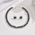 Close-up of sparkling black and white crystal necklace and earring set on white fabric - 1479 Black