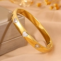 Bracelet jonc doré en acier poli avec trois zircons en forme de cœur sur un écrin - Or Cœur Zircone Blanche