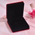 Vue macro d'un écrin à bijoux en velours rouge avec doublure noire et touches florales - Boîte Cadeau Carrée Rouge