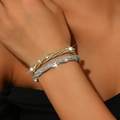 Detail of twisted gold and silver bracelets set with sparkling rhinestones on wrist - Gold and Silver Set