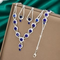 Detailed view of luxury silver-toned jewelry set with deep blue crystals on green silk - Necklace Earrings And Bracelet Combination / Sapphire Blue
