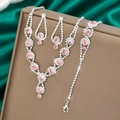 Macro shot of silver-tone necklace set with pink rhinestones on a dark green satin surface - Necklace Earrings And Bracelet Combination / Pink