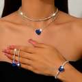 Vista detallada de una modelo con collar de doble capa de corazón azul y aretes a juego - Collar, Pendientes y Pulsera (1514) / Azul zafiro