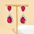 Detalle de pendientes de gota rojo rosa con flecos plateados en soporte de exhibición - Fucsia