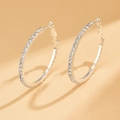 Macro shot of silver hoop earrings featuring micro-pave crystal diamonds on the metal surface - Silver (Size 4)