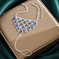 Detalle de pulsera de anillo plateada con pedrería azul sobre un fondo de seda verde - Estilo Azul Real (1292)