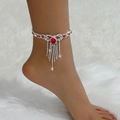 Detalle de una tobillera plateada con pedrería brillante y borlas de cristal rojo - Rojo