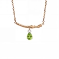 Detailed close-up of a pear-cut green gemstone pendant with a branch-like gold bar design - August-Olive Green