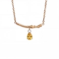 Close-up of golden branch pendant with a pear-cut yellow gemstone on a fine chain - November-Yellow
