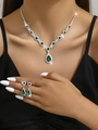 Close-up of teardrop emerald crystal necklace and earrings set worn by a fashion model - Peacock Green