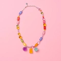 Detalle de collar de cuentas coloridas con colgantes de osito y flores en fondo rosa - Rosa Translúcido