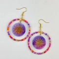 Detailed macro view of bohemian beaded hoop earrings with sun pattern and purple charms - Round Red Style