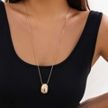 Detail of a minimalist gold comma drop pendant on a sleek chain worn over a black top - Long Egg Shaped Necklace (6125) / Gold