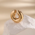 Detailed view of thick C-shaped gold ear cuff with polished mirror finish on stone - Gold
