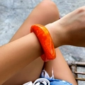 Macro detail of amber resin bracelet showing marble-like textures and polished surface - Orange (2252)