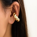 Dettaglio di un ear cuff dorato con trama a spirale indossato sulla cartilagine dell'orecchio - Stile Attorcigliato / Oro