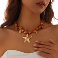 Dettaglio della collana di perle con ciondoli dorati a forma di stella marina e conchiglia - Collana (6675) / Arancione