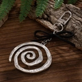 Makroansicht von silbernem Spiral-Schlüsselanhänger mit schwarzer Schleife auf Holz - Antiksilber