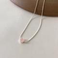 Nahaufnahme eines rosa Emaille-Smiley-Anhängers an einer silbernen Schlangenkette - Rosa Stil (XL0479)