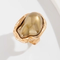 Macro d'une bague baroque dorée irrégulière avec une grande résine ambre translucide - Bague en perle artificielle de couleur café