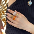 Detail of fashion jewelry set with gold metal rings and amber resin ring on model hand - Light Gold Style (5572)
