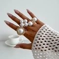 Detailed view of chunky faux pearl ring set with gold metal bands on model's hand - Three Artificial Pearl Petal Ring (6265) / Three-Piece Set / Light gold