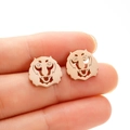 Macro view of rose gold lion stud earrings on a fingertip showing small delicate size - Tiger / Lion Head (687) / Rose Gold