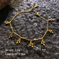 Goldenes Noten-Armband aus Edelstahl mit sieben Anhängern auf dunklem Steinhintergrund - Musiknote Armband / Gold Musiknote Armband
