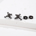 Primer plano detallado de pendientes de rana en negro mate sobre piedra con textura - Forma Rana (487) / Negro