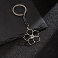 Silver stainless steel keychain with minimalist hollow flower pendant on a dark stone surface - Hollow Five-Petal Flower (198)