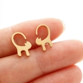 Macro shot of minimalist gold cat stud earrings on a fingertip for size reference - Gold