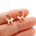 Macro view of rose gold long tail cat earrings held on a finger for size reference - Rose Gold