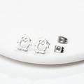 Detailed macro view of penguin earrings with heart cutouts on a minimalist white stand - Steel