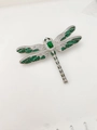 Dettaglio macro di una spilla a libellula con pietre verde smeraldo e pavé di zirconi - Verde