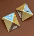 Vista macro de pendientes piramidales geométricos con acabados bicolores en oro y plata - Estilo de Empalme Geométrico en Pirámide